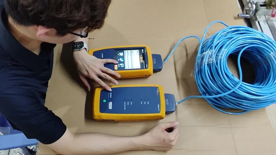 Technician testing a coil of network cable with a cable certifier
